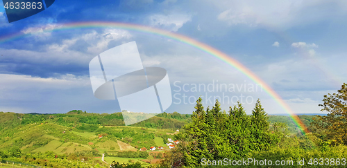 Image of Spring rural rainbow landscape, view of green meadows and hills