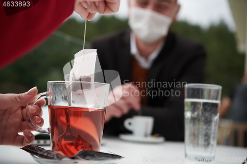 Image of couple with protective medical mask  having coffee break in a re