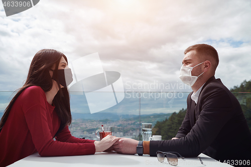 Image of couple with protective medical mask  having coffee break in a re