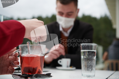 Image of couple with protective medical mask  having coffee break in a re