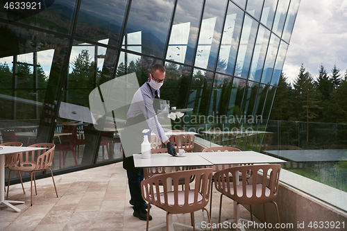 Image of Waiter cleaning the table with Disinfectant Spray in a restauran