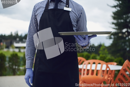 Image of waiter in a medical protective mask serves  the coffee in restau