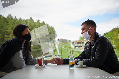 Image of couple in restaurant wearing corona virus  medical protective fa