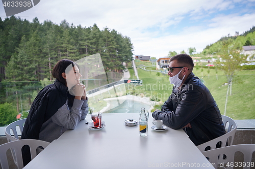 Image of couple in restaurant wearing corona virus  medical protective fa