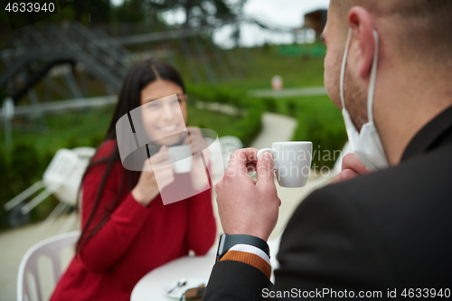 Image of couple with protective medical mask  having coffee break in a re