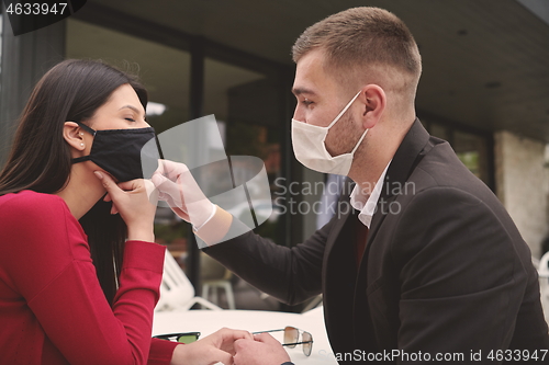 Image of couple with protective medical mask  having coffee break in a re