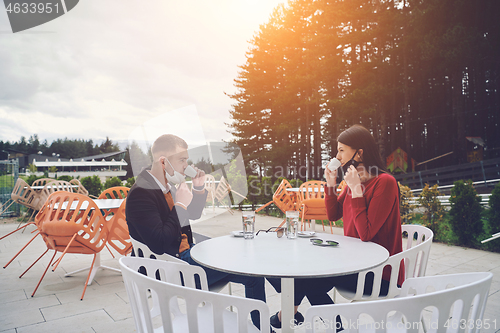 Image of couple with protective medical mask  having coffee break in a re