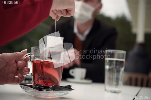 Image of couple with protective medical mask  having coffee break in a re