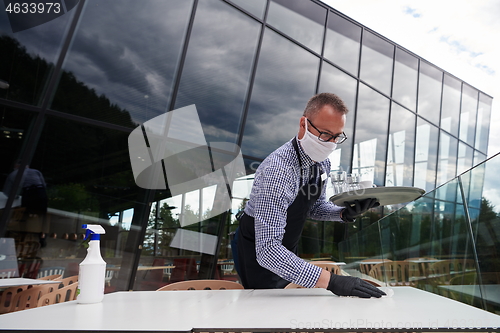 Image of Waiter cleaning the table with Disinfectant Spray in a restauran