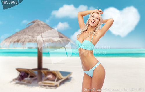 Image of young woman posing in bikini on beach