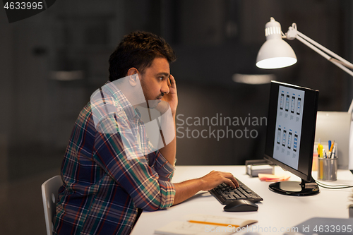 Image of creative man with computer working at night office