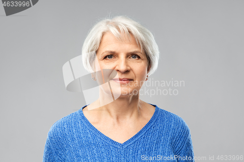 Image of portrait of senior woman in blue sweater over grey