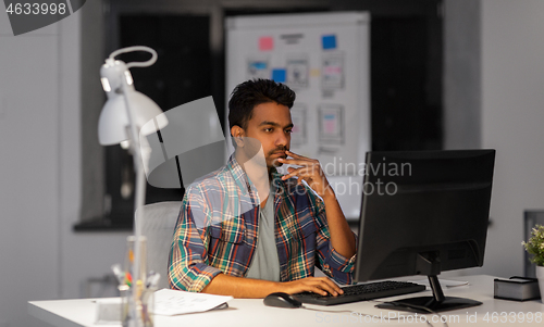 Image of creative man with computer working at night office