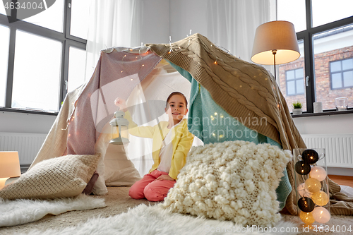 Image of little girl with lantern in kids tent at home