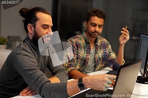 Image of creative team with computer working late at office