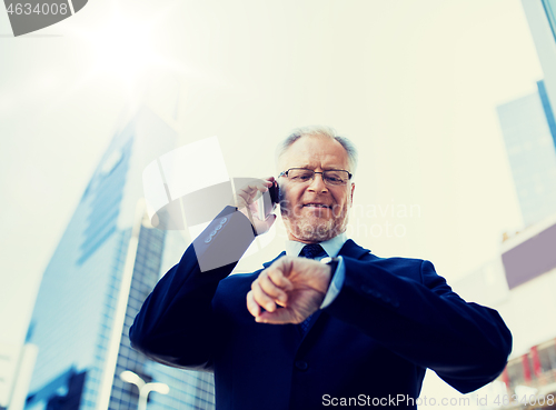 Image of senior businessman calling on smartphone in city