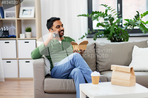 Image of smiling indian man eating takeaway food at home