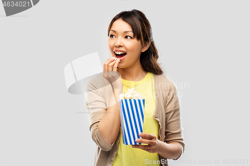 Image of smiling asian woman eating popcorn