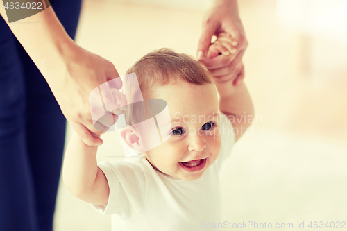 Image of happy baby learning to walk with mother help