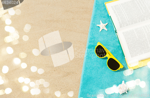 Image of sunglasses and book on beach towel on sand