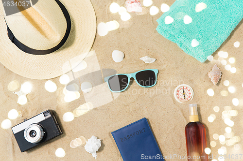 Image of camera, passport, sunglasses and hat on beach sand