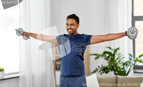 Image of indian man exercising with dumbbells at home