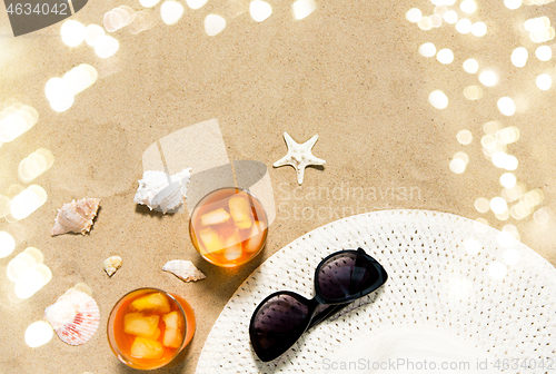 Image of cocktails, sun hat and sunglasses on beach sand