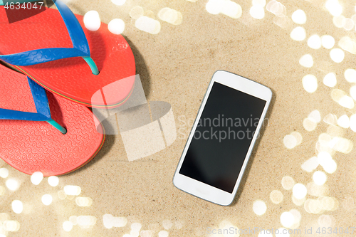 Image of smartphone and flip flops on beach sand