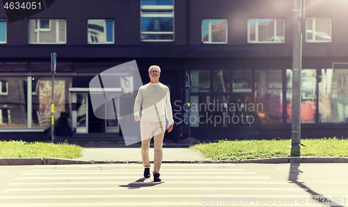 Image of senior man walking along city crosswalk