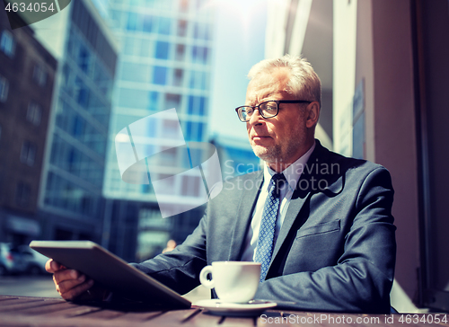 Image of senior businessman with tablet pc drinking coffee