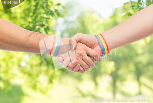 Image of hands with gay pride wristbands make handshake