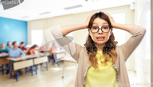 Image of stressed female student holding to head at school