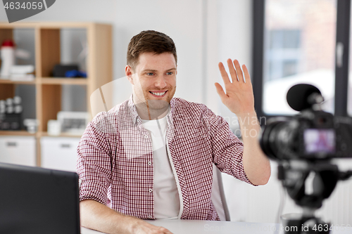 Image of male blogger with camera videoblogging at home