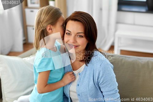 Image of daughter whispering secret to mother at home