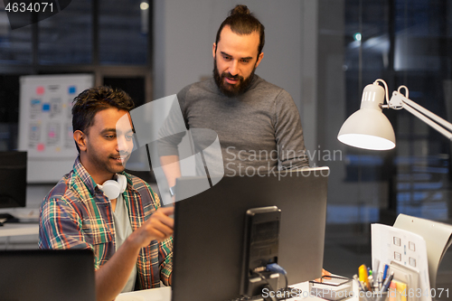 Image of creative team with computer working late at office