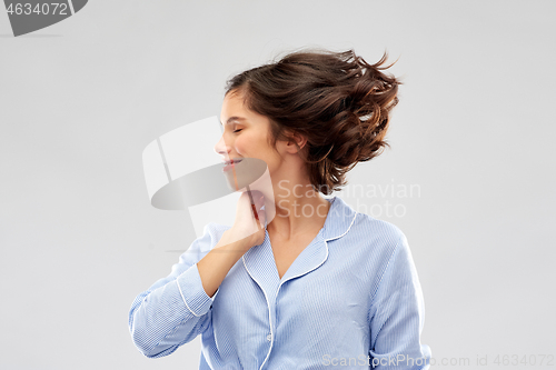 Image of happy young woman in pajama over grey background