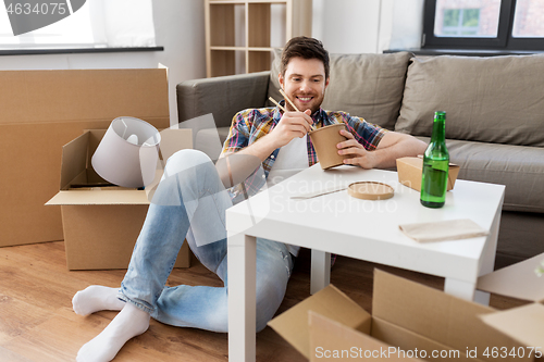 Image of smiling man eating takeaway food at new home