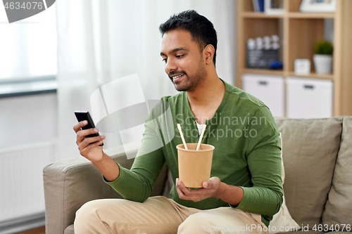 Image of smiling indian man eating takeaway food at home