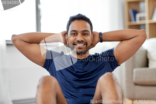 Image of indian man making abdominal exercises at home