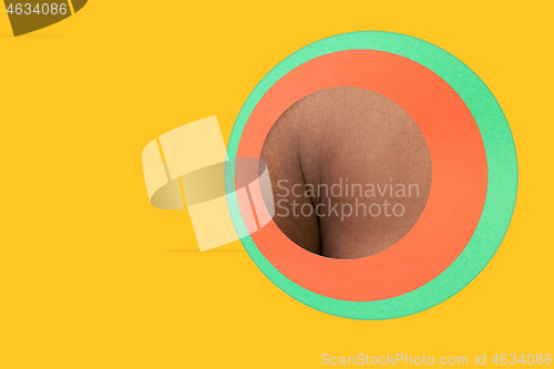 Image of Body of african-american man peeking throught circle in yellow background