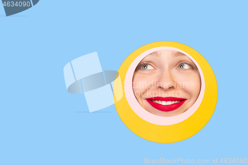 Image of Female face with red lips peeking throught circle in blue background