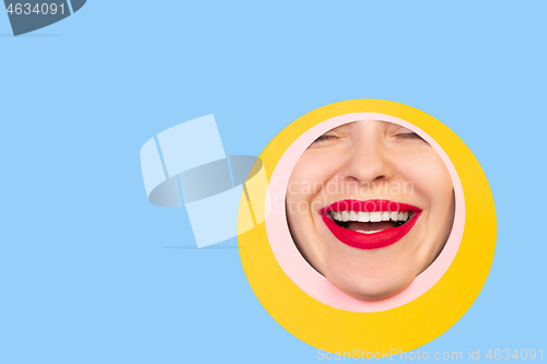 Image of Female face with red lips peeking throught circle in blue background