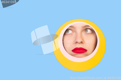 Image of Female face with red lips peeking throught circle in blue background