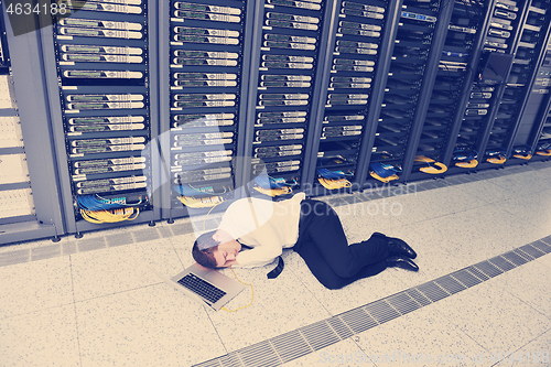 Image of businessman with laptop in network server room