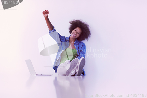 Image of african american woman sitting on floor with laptop