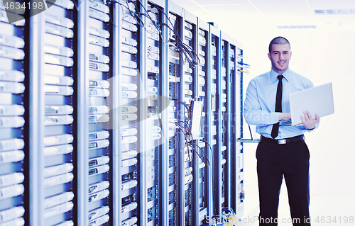 Image of businessman with laptop in network server room