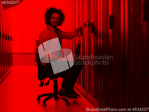 Image of engineer working on a laptop in server room