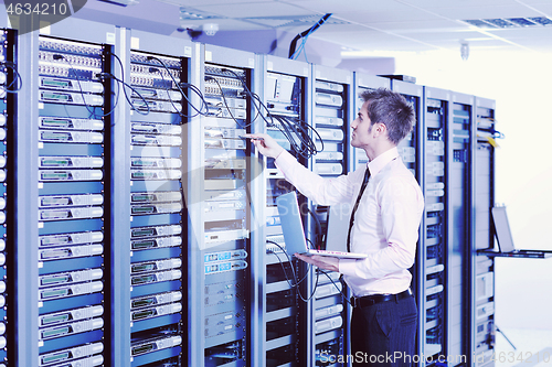 Image of businessman with laptop in network server room