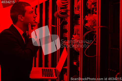 Image of businessman with laptop in network server room