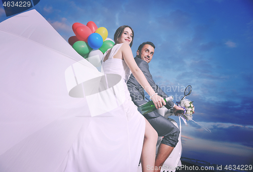 Image of just married couple on the beach ride white scooter